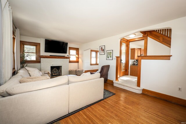 living area featuring a fireplace, baseboards, and wood finished floors