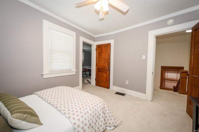 bedroom with light colored carpet, crown molding, baseboards, and ceiling fan