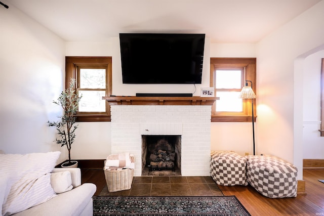 living room with a fireplace, wood finished floors, baseboards, and a wealth of natural light