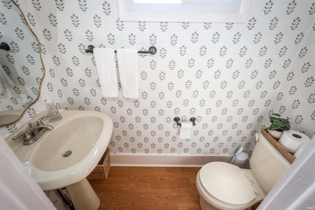 bathroom with a sink, toilet, a skylight, and wallpapered walls