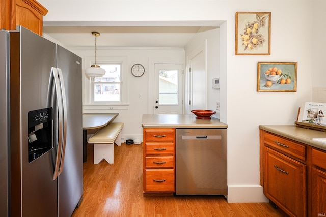 kitchen featuring light countertops, light wood finished floors, brown cabinets, and appliances with stainless steel finishes