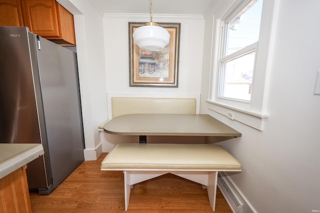 dining space with breakfast area, light wood-type flooring, baseboards, and ornamental molding