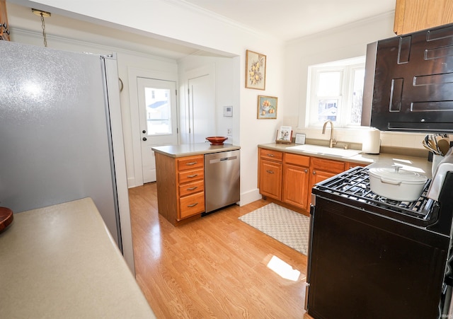 kitchen with crown molding, light wood-type flooring, appliances with stainless steel finishes, plenty of natural light, and a sink