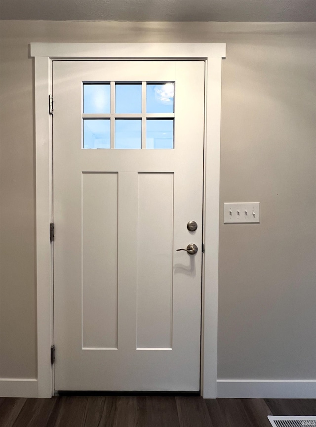 doorway featuring baseboards and dark wood-type flooring