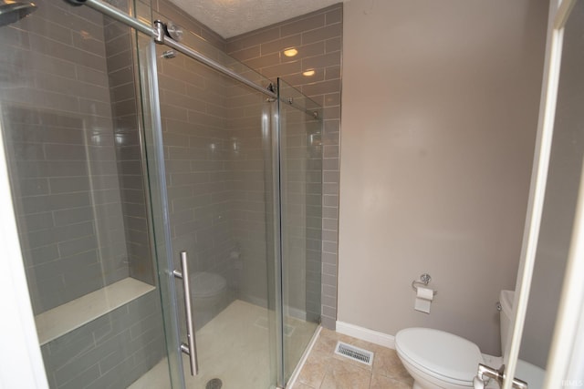 bathroom featuring visible vents, baseboards, toilet, a stall shower, and tile patterned floors