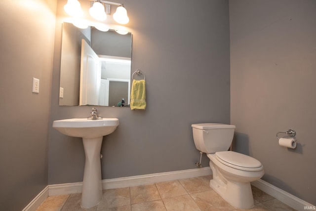 half bathroom featuring tile patterned flooring, toilet, and baseboards