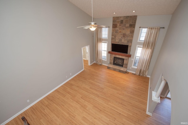 unfurnished living room with light wood-style flooring, a fireplace, baseboards, and ceiling fan