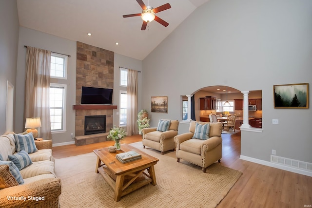 living room with visible vents, ornate columns, arched walkways, ceiling fan, and light wood-type flooring