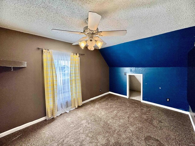 additional living space featuring baseboards, a textured ceiling, carpet floors, and ceiling fan