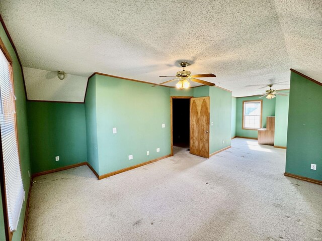 carpeted spare room with ornamental molding, a textured ceiling, baseboards, and a ceiling fan