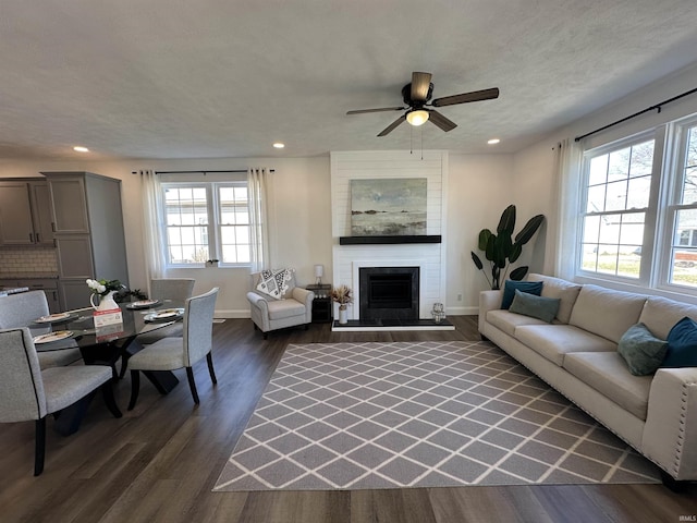 living area with recessed lighting, plenty of natural light, dark wood-style floors, and a fireplace