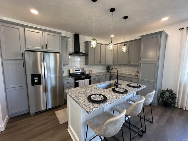 kitchen featuring a sink, appliances with stainless steel finishes, gray cabinets, and wall chimney range hood