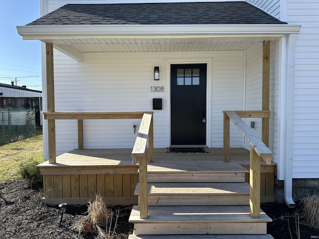 entrance to property featuring fence and a shingled roof