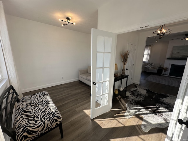 sitting room featuring wood finished floors, visible vents, baseboards, a fireplace, and a notable chandelier