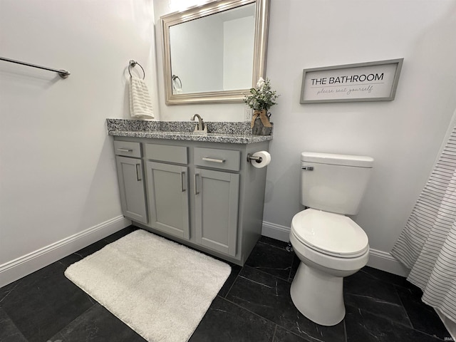 bathroom with toilet, vanity, and baseboards