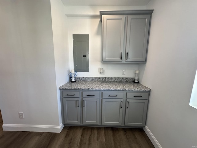 kitchen featuring dark wood finished floors, electric panel, baseboards, and gray cabinets