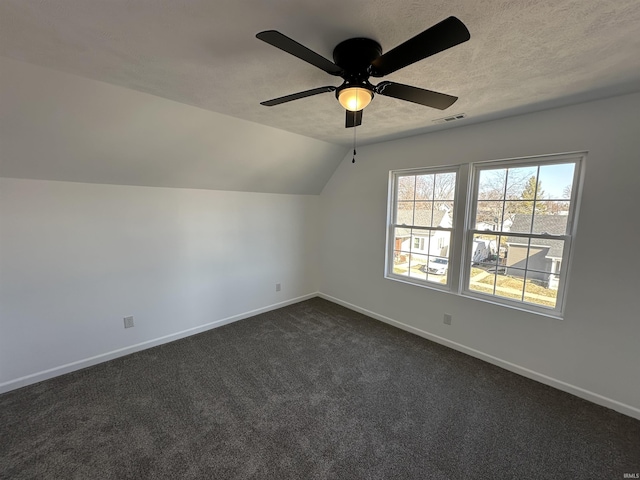 bonus room with visible vents, a textured ceiling, dark carpet, baseboards, and lofted ceiling