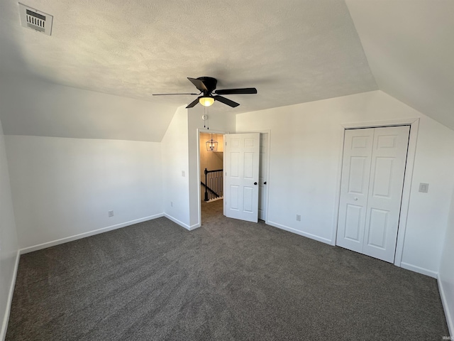 additional living space with baseboards, visible vents, dark carpet, and a textured ceiling