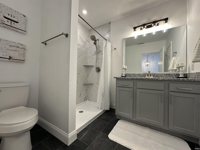 bathroom featuring a stall shower, toilet, vanity, and baseboards