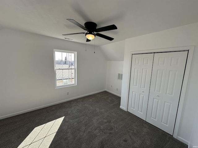 unfurnished bedroom featuring a ceiling fan, baseboards, vaulted ceiling, a closet, and dark carpet