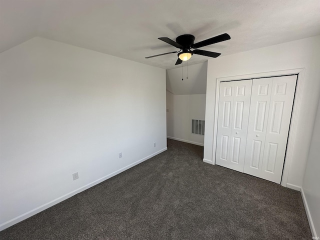 unfurnished bedroom with visible vents, baseboards, lofted ceiling, and dark colored carpet