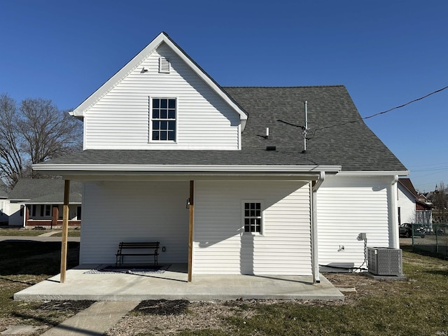 back of house featuring cooling unit, roof with shingles, and a patio area