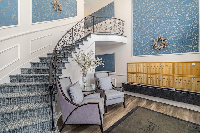 interior space featuring mail area, wood finished floors, wainscoting, and a decorative wall