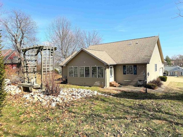 rear view of property featuring a patio area, a yard, a shingled roof, and entry steps