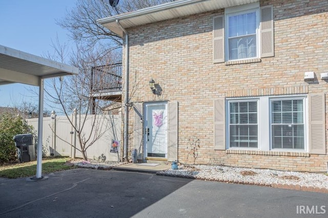 property entrance featuring fence and brick siding