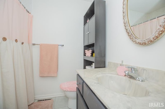 bathroom with vanity, baseboards, visible vents, tile patterned floors, and toilet