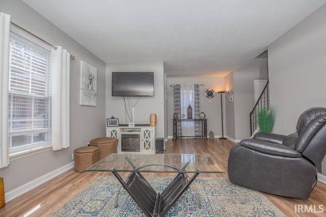 living room with stairway, baseboards, and wood finished floors