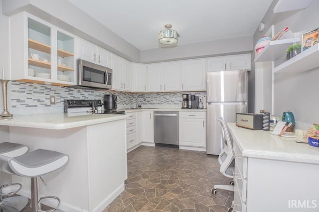 kitchen with appliances with stainless steel finishes, white cabinetry, glass insert cabinets, and a peninsula