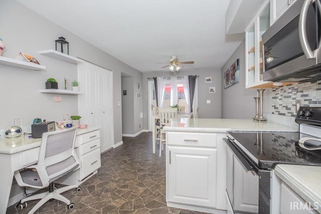 kitchen featuring stainless steel microwave, range with electric cooktop, light countertops, and white cabinetry