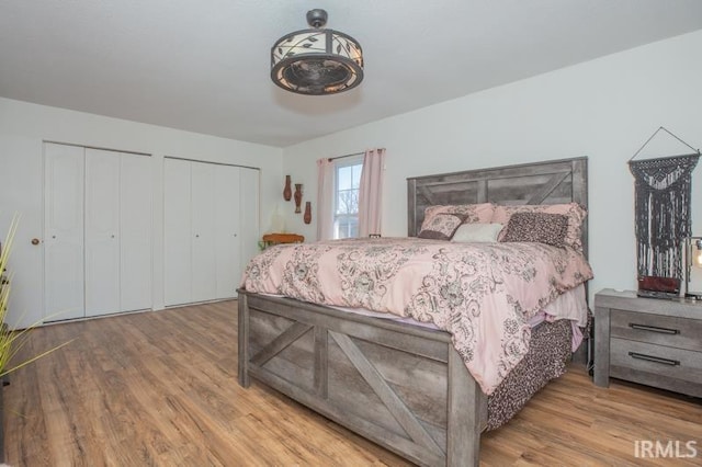 bedroom with two closets and wood finished floors