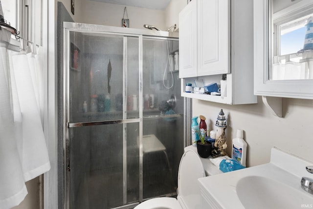 bathroom with toilet, a stall shower, and a sink