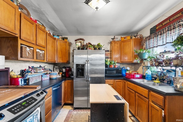 kitchen featuring light tile patterned floors, brown cabinetry, a sink, decorative backsplash, and appliances with stainless steel finishes