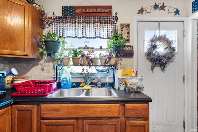 kitchen with dark countertops, brown cabinetry, a wealth of natural light, and a sink