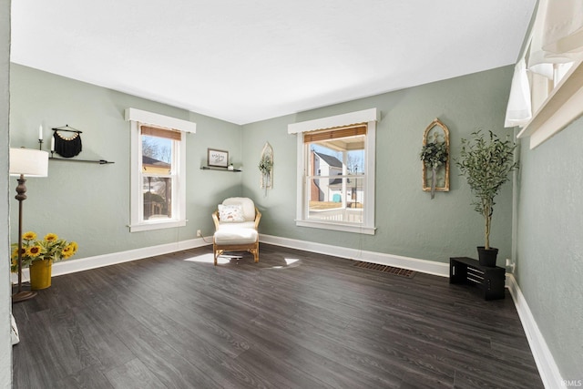 sitting room with visible vents, baseboards, and wood finished floors