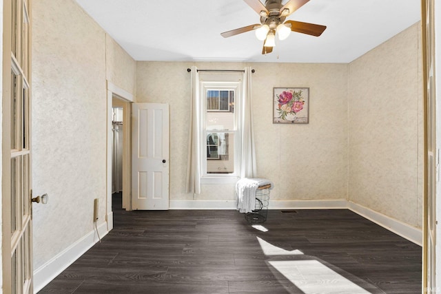 unfurnished room with baseboards, dark wood finished floors, and a ceiling fan