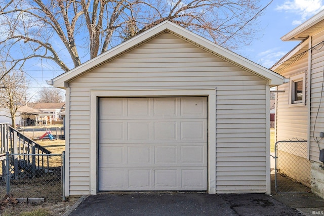 detached garage featuring fence and driveway