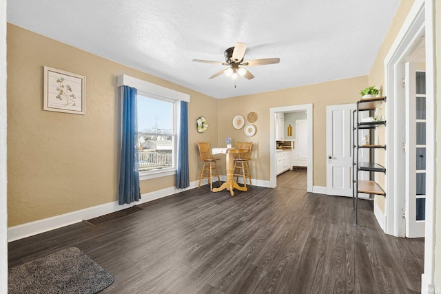 interior space featuring visible vents, baseboards, dark wood-style flooring, ceiling fan, and a textured ceiling