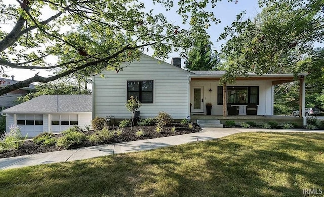 view of front of home with a garage, a porch, a chimney, and a front yard