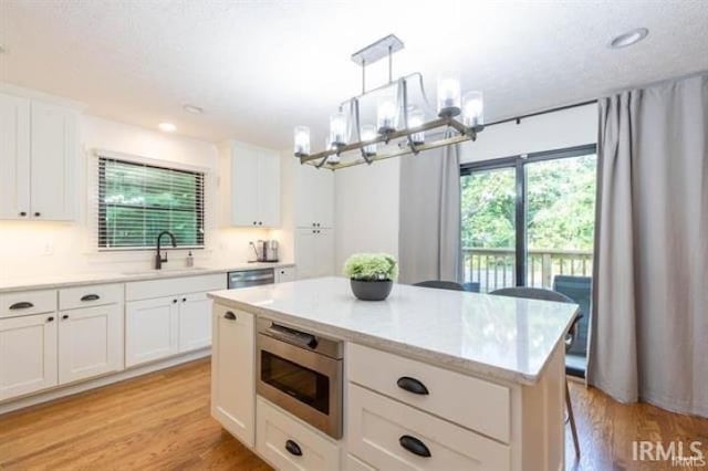 kitchen with white cabinetry, light wood-type flooring, stainless steel appliances, and a sink