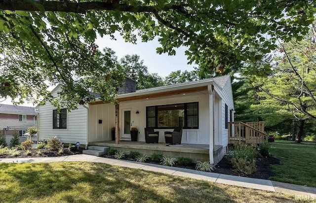 view of front of home with a porch, a front lawn, and a chimney