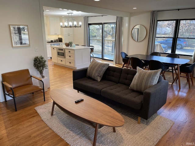 living area featuring recessed lighting, a notable chandelier, and light wood-style flooring