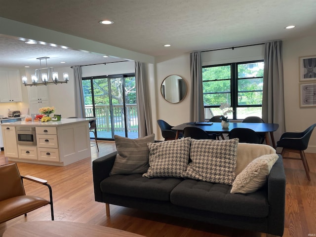 living room with light wood-style flooring, recessed lighting, a chandelier, and a textured ceiling