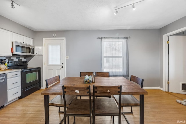 dining area featuring light wood-style floors, baseboards, and a textured ceiling