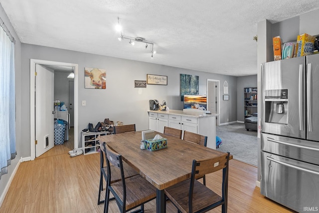 dining area featuring baseboards, visible vents, light wood-type flooring, and a textured ceiling