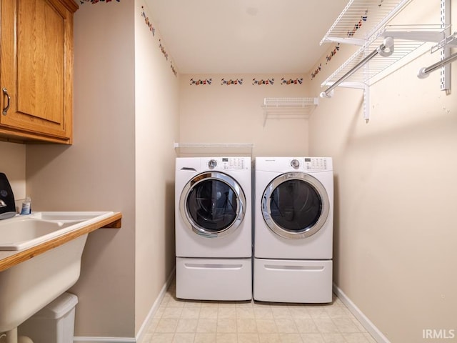 laundry area with baseboards, cabinet space, and washing machine and clothes dryer