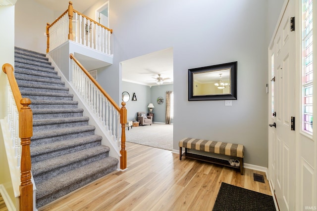 foyer with stairs, a towering ceiling, baseboards, and light wood finished floors